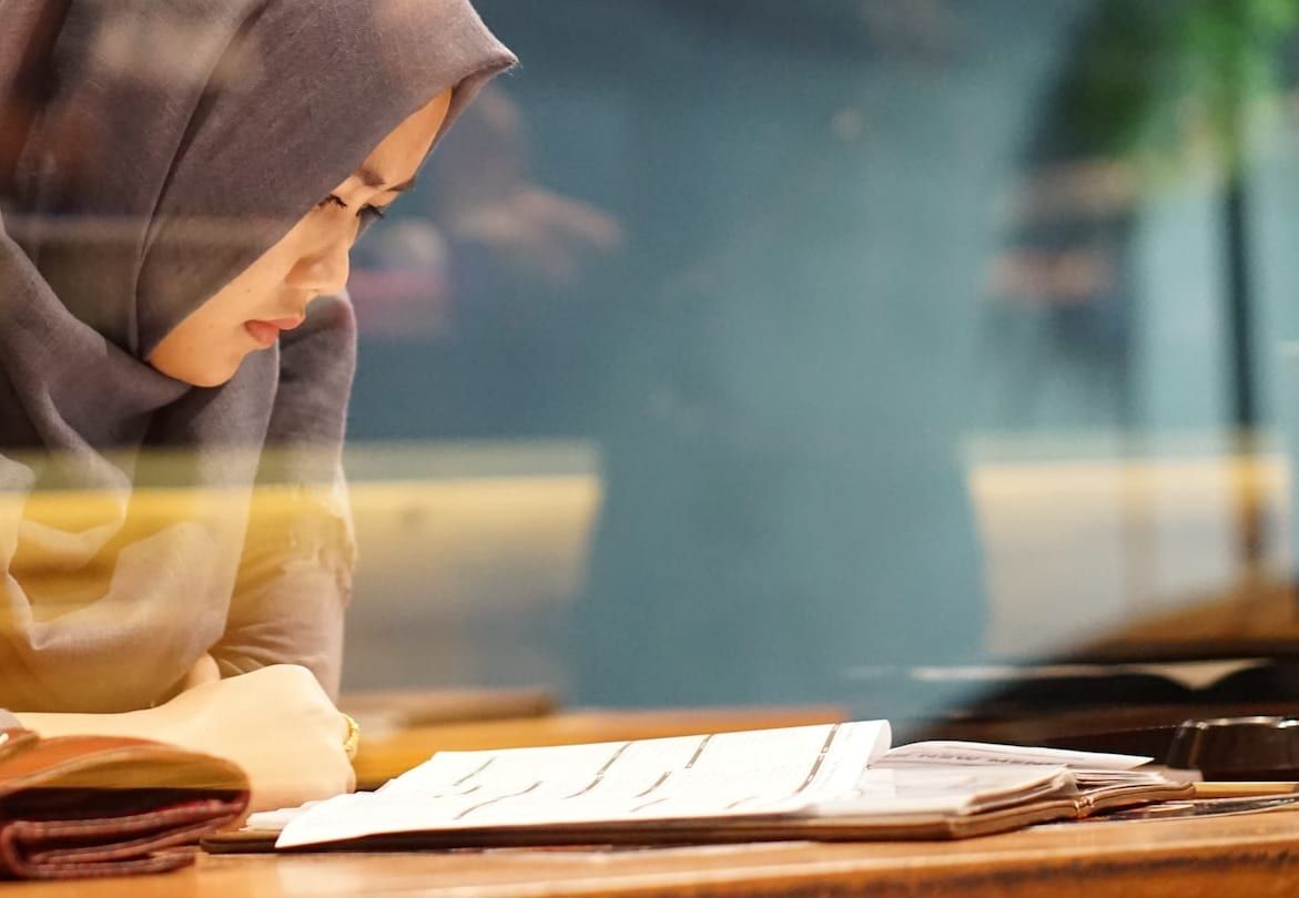 A woman working through papers and a notebook at a table