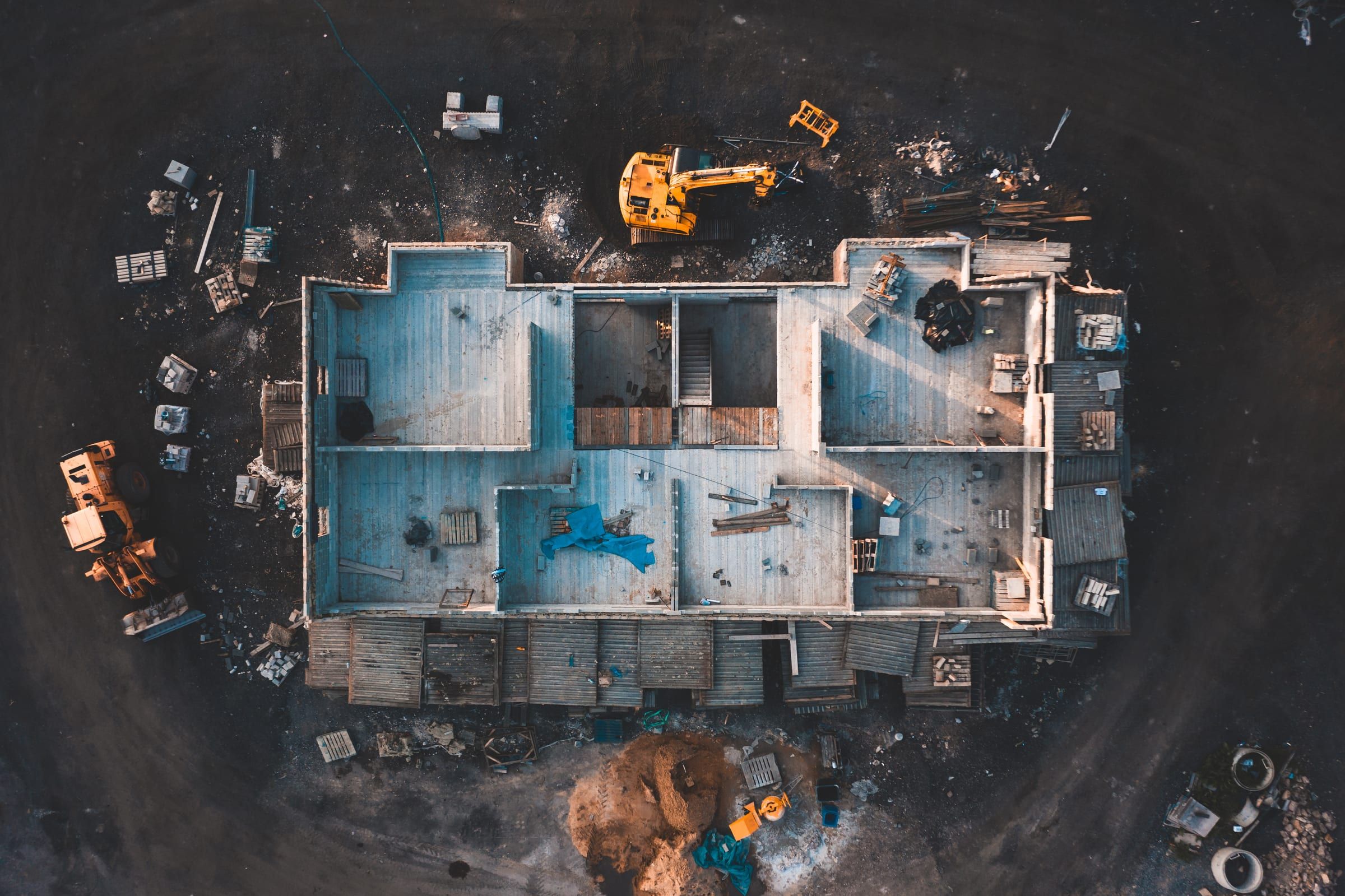 A building site seen from above, with excavators beside the foundations